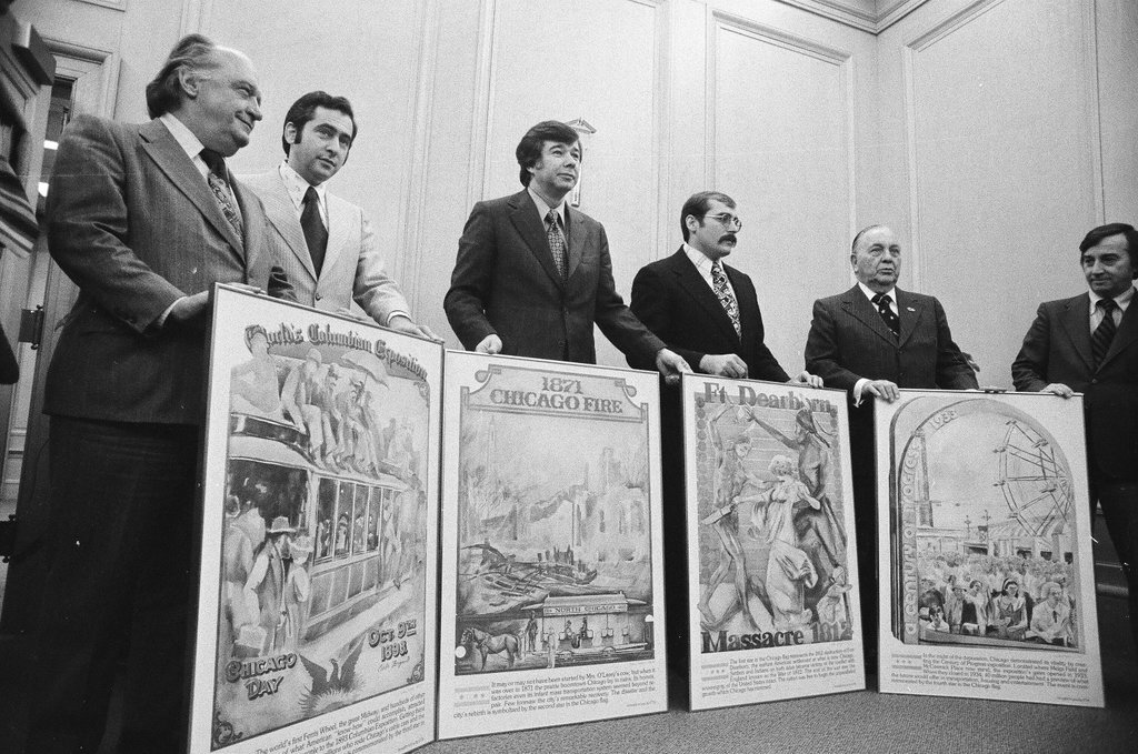 Men pose with posters of historical events - Chicago Sun-Times