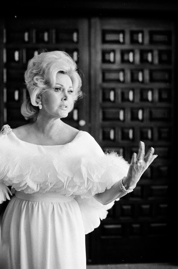 Zsa Zsa Gabor poses in a white dress in a hotel room - Fred Stein for Chicago Daily News