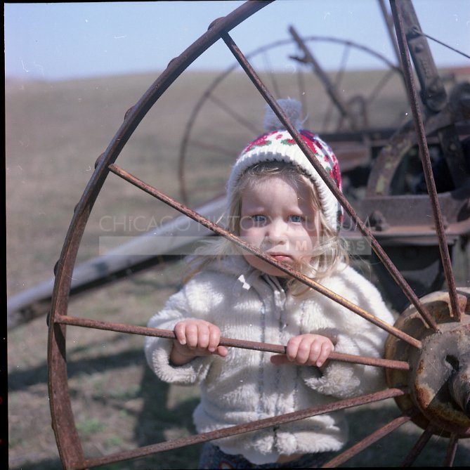 Toddler posed by wagon wheel - Maier, Vivian