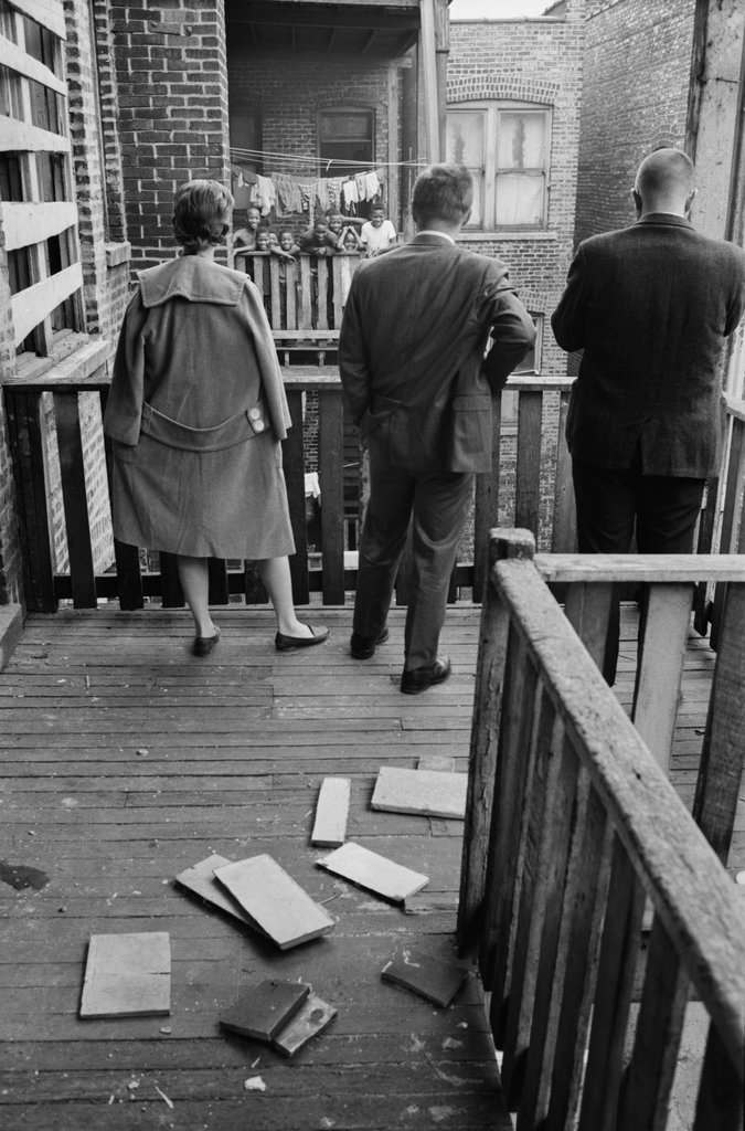 Group of children standing under laundry hanging to dry on the rear balcony of an apartment building - Haun, Declan, 1937-1994