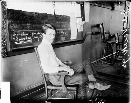 Joseph Vacek, Jr., accused murderer, sitting in front of a blackboard in a room, confessed to murdering his father, Joseph Vacek, Sr. - Chicago Daily News, Inc.