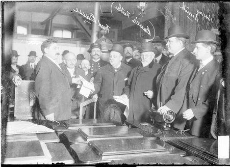 Mayor Fred Busse, his father Gustave Busse, his brother George Busse, and Harry Smith standing with other men in a room with sewing machines - Chicago Daily News, Inc.