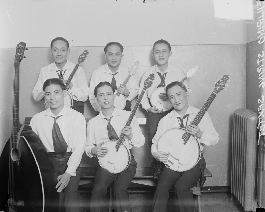 Six members of a Filipino string sextet sitting in a room - Chicago Daily News, Inc.