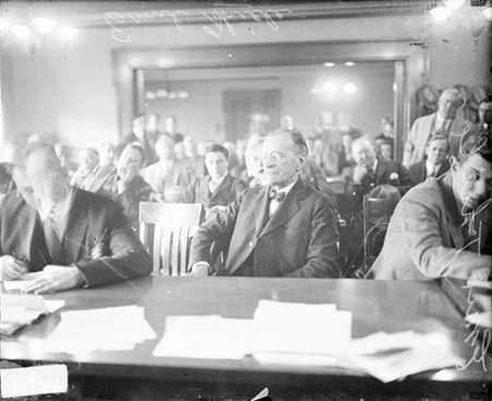 Emil Thiele, sitting at a long table in a crowded courtroom, looking to the left of the camera - Chicago Daily News, Inc.