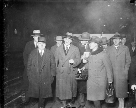Newspaper publisher Harold McCormick walking along a railroad platform at a train station, being followed by the press - Chicago Daily News, Inc.