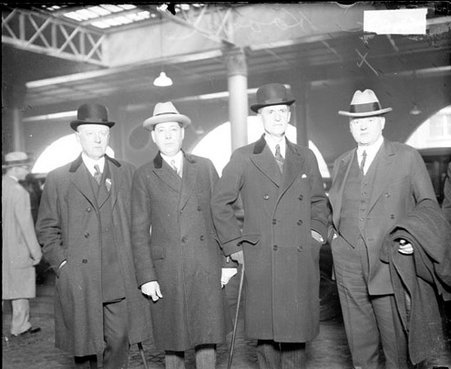 Secretary of Commerce Herbert Hoover standing with three unidentified men in a train station - Chicago Daily News, Inc.