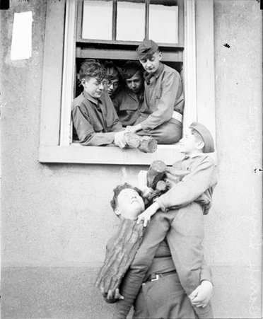Reserve Officer Training Corps trainee holding a boy on his shoulder beneath a window, four trainees leaning out the window - Chicago Daily News, Inc.
