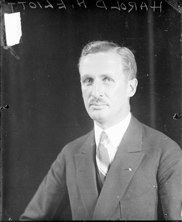 Harold H. Elliott looking toward the camera, sitting in front of a dark backdrop in a room - Chicago Daily News, Inc.