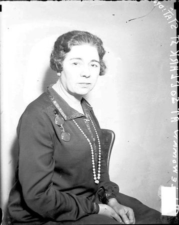 Unidentified policewoman looking toward the camera, sitting in a room at the police station at 625 South Clark Street, Loop community area - Chicago Daily News, Inc.
