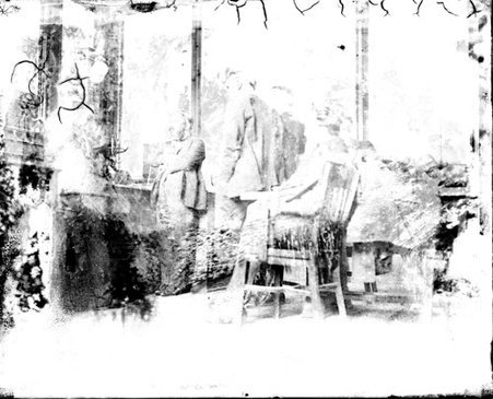 Men standing and sitting in a room, image bleached out - Chicago Daily News, Inc.