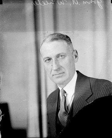 John A. Wheeler looking toward the camera and sitting in front of a light-colored backdrop - Chicago Daily News, Inc.