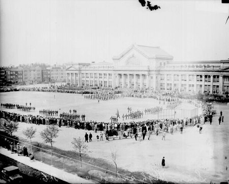 Regiments of the Senn High School R. O. T. C. marching band marching on a field in front of Senn High School - Chicago Daily News, Inc.