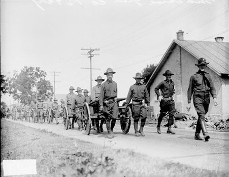 Line of soldiers in the One hundred twenty-nine Infantry wheeling carts on a road - Chicago Daily News, Inc.