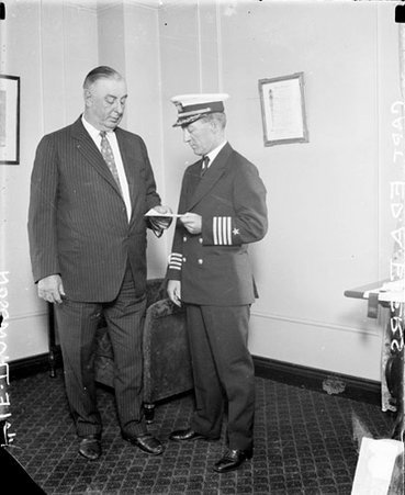 Mayor William Hale Thompson holding a piece of paper with a military captain, standing in a room - Chicago Daily News, Inc.