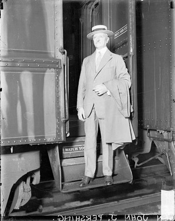 General John J. Pershing standing on the steps of a passenger train car in a train station, light exposure - Chicago Daily News, Inc.