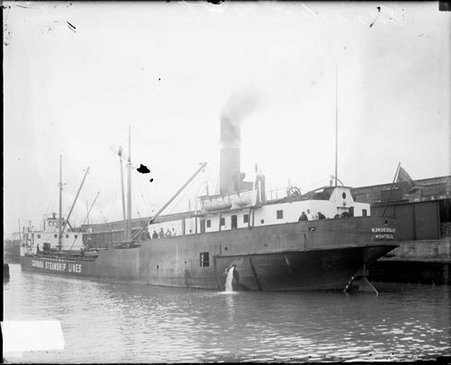 Steamship Kindersley moored to a dock in a body of water, viewed from across the water - Chicago Daily News, Inc.