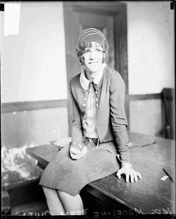 Mrs. Madeline Beem Owen looking to her left, sitting on a table in a room - Chicago Daily News, Inc.