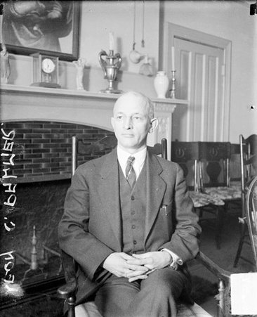 Leon C. Palmer looking to his right, sitting in front of a fireplace in a room - Chicago Daily News, Inc.