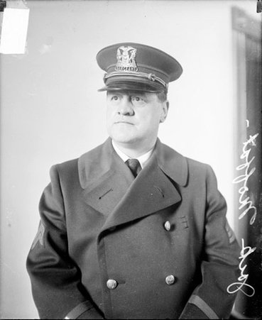 Police officer Jack Moffat looking to the left of the camera, sitting in a room - Chicago Daily News, Inc.
