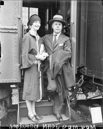 Mr. and Mrs. John Borden standing on the steps of a passenger train car in a railroad station - Chicago Daily News, Inc.