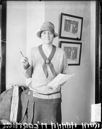 Mrs. Ruth Hanna McCormick Simms standing in front of a wall in a room, dark exposure - Chicago Daily News, Inc.