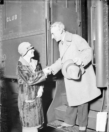 Maurice Ravel standing on the steps of a passenger train car, shaking hands with Sarah Brewster - Chicago Daily News, Inc.
