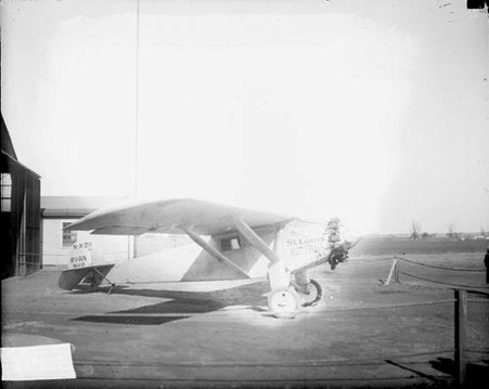 Propeller airplane sitting in front of a hanger on a field - Chicago Daily News, Inc.