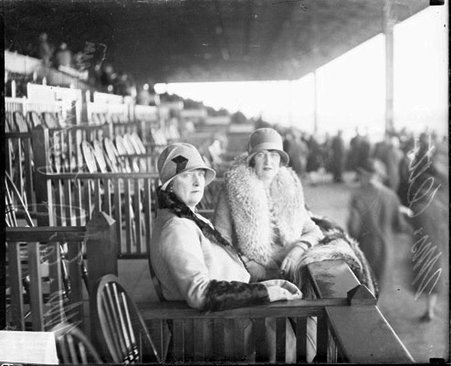 Mrs. E. J. Lehmann and an unidentified woman sitting in box seats at an outdoor stadium - Chicago Daily News, Inc.