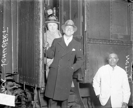 Jake Shubert and Al Jolson standing on the steps of a passenger train car in a railroad station - Chicago Daily News, Inc.