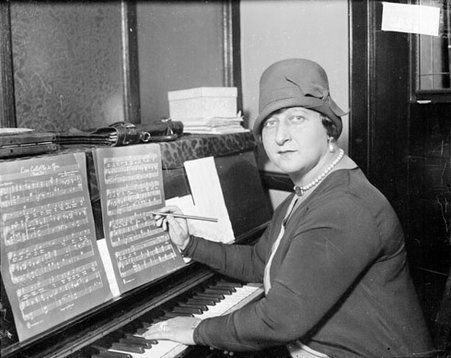 Songwriter Mrs. Goodman sitting at a piano in a room - Chicago Daily News, Inc.