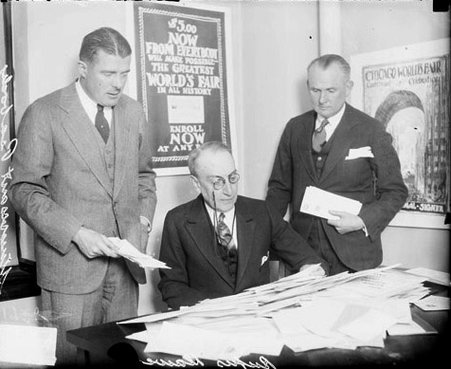 Rufus Dawes sitting at a desk in a room, Elmer Rich and Stuyvesant Peabody standing on either side of him, light exposure - Chicago Daily News, Inc.