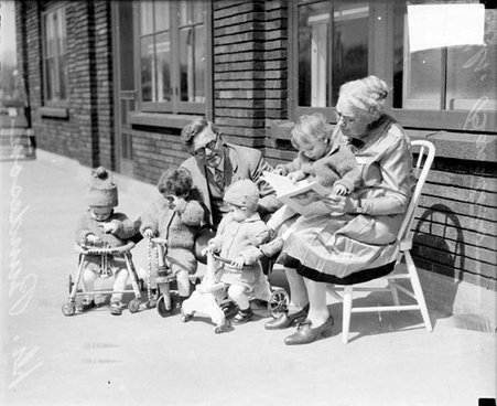 Dr. Rhoda Pike Barstow and Dr. Herman N. Bundesen posing with a group of children in front of a building, dark exposure - Chicago Daily News, Inc.