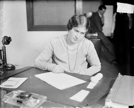 Betty J. Shimon (called the butter and egg woman) writing on a piece of paper, sitting at a desk - Chicago Daily News, Inc.