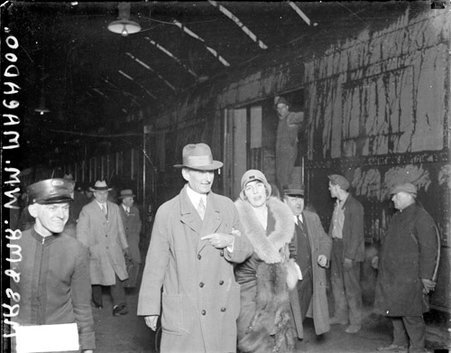 William G. McAdoo and his wife walking in a railroad station - Chicago Daily News, Inc.