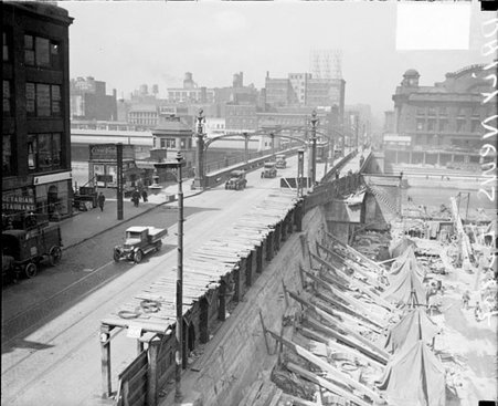 Automobiles and a bridge next to the construction site of the Civic Opera House - Chicago Daily News, Inc.