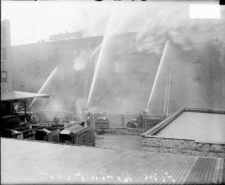 Firefighters spraying water from hoses at a fire in a building, dark exposure - Chicago Daily News, Inc.