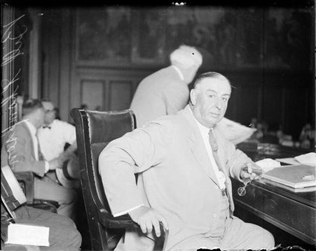 William Hale Thompson looking toward the camera, sitting at a table in a courtroom - Chicago Daily News, Inc.
