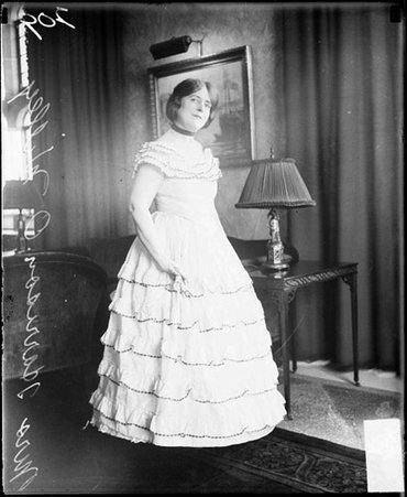 Mrs. Harrison O. Willey wearing a costume dress, standing in a room - Chicago Daily News, Inc.