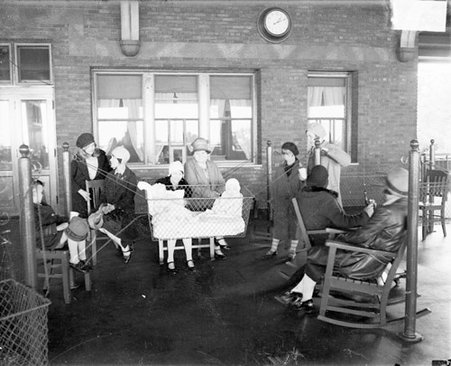 Women, children, and babies sitting and standing in an open-air area at the Chicago Daily News Sanitarium, dark exposure - Chicago Daily News, Inc.