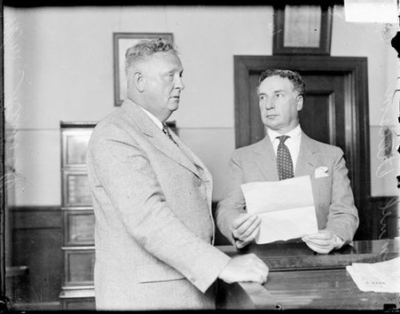 William F. Russell standing with Samuel Ettelson at a table in an office - Chicago Daily News, Inc.