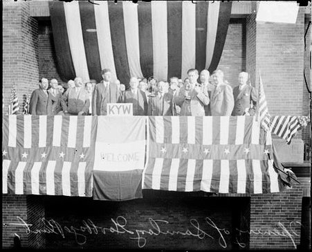 Large group of men standing on a decorated platform during a ceremony for the opening of a garbage plant in the Sanitary District, light exposure - Chicago Daily News, Inc.