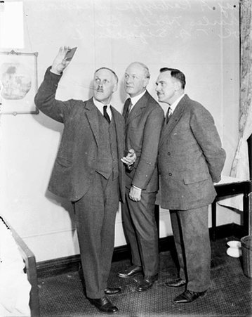 Major A. Radcliffe Dugmore showing Charles Hull Ewing and Colonel T. A. Siqueland an object in his hand - Chicago Daily News, Inc.