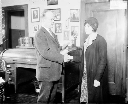 Judge William Lindsay and an unidentified woman shaking hands, standing in a room - Chicago Daily News, Inc.