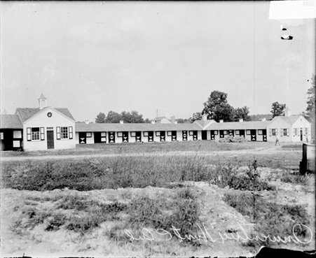 One-story buildings at the Onwentsia Hunt Club, viewed at an angle from across a field, dark exposure - Chicago Daily News, Inc.