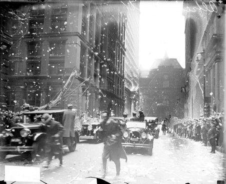 Alfred E. Smith parade, automobiles driving on a street and crowds lining the street, confetti falling through the air and littering the ground - Chicago Daily News, Inc.
