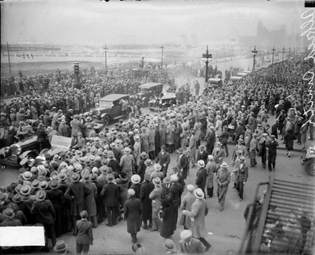 Alfred E. Smith parade, crowds lining a street watching automobiles surrounded by men standing near and on the rails of the automobiles - Chicago Daily News, Inc.