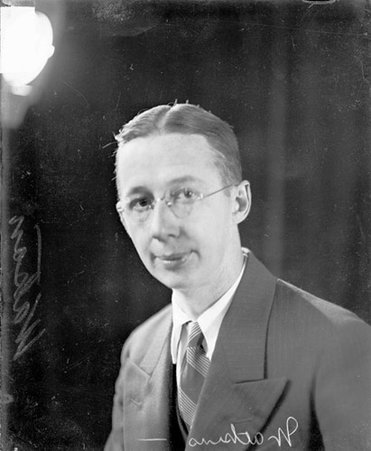 P. S. Watkins, Chicago Daily News promotions department, looking toward the camera, sitting in front of a dark in a room - Chicago Daily News, Inc.