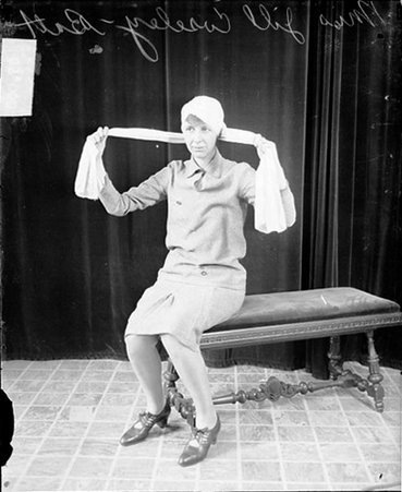 Miss Jill Coseley Batt wrapping a large piece of fabric around her head - Chicago Daily News, Inc.