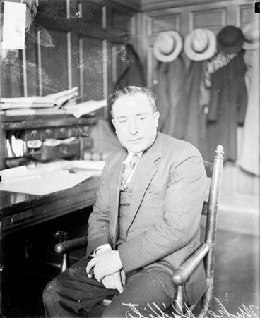 Mike Divito looking down and to his left, sitting at a desk in a room - Chicago Daily News, Inc.