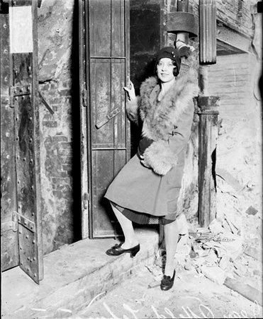 Jean Alffeld Lehmann standing in front of a dilapidated building - Chicago Daily News, Inc.